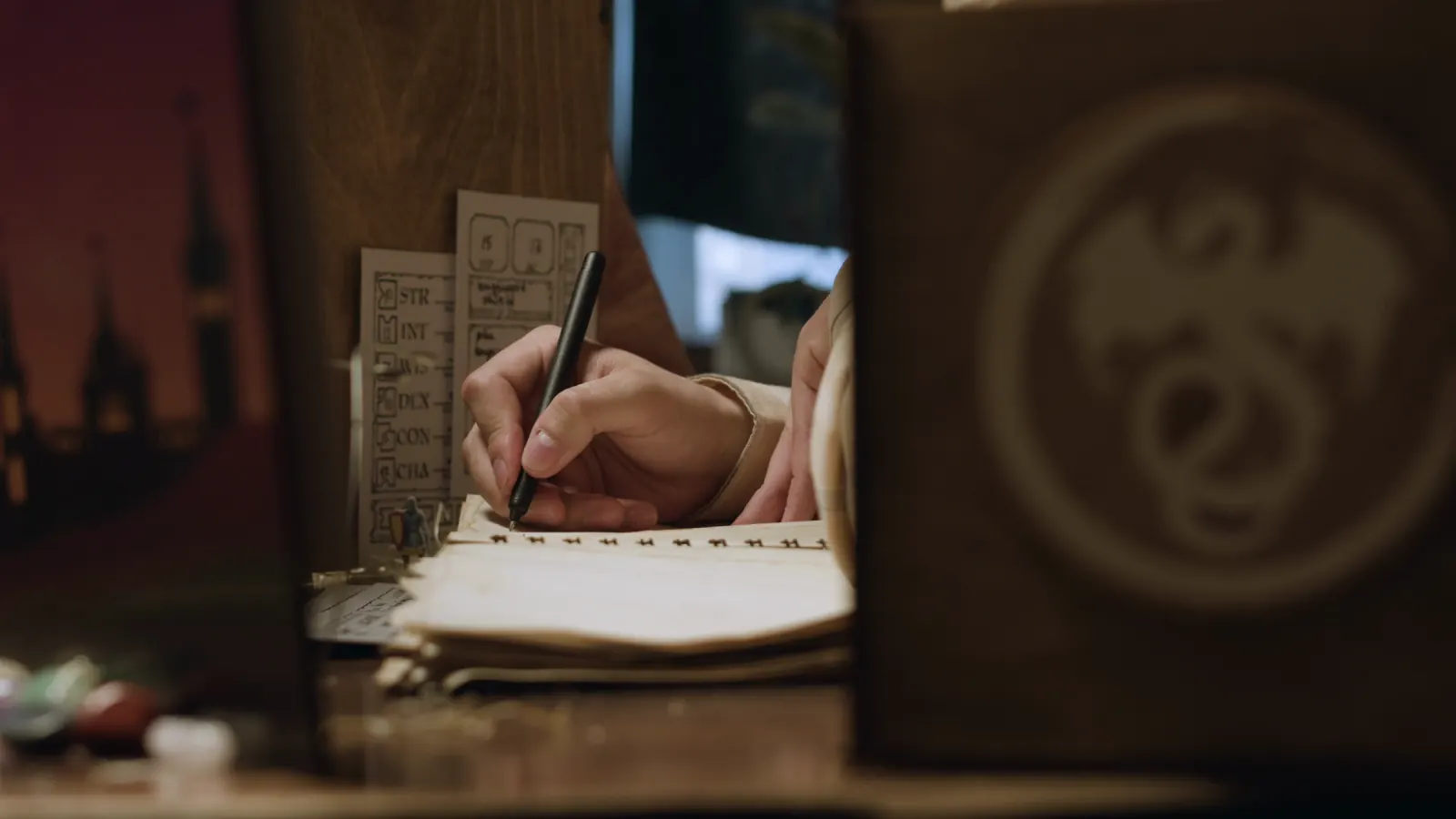 A writer's hands working in a notebook by lamplight.